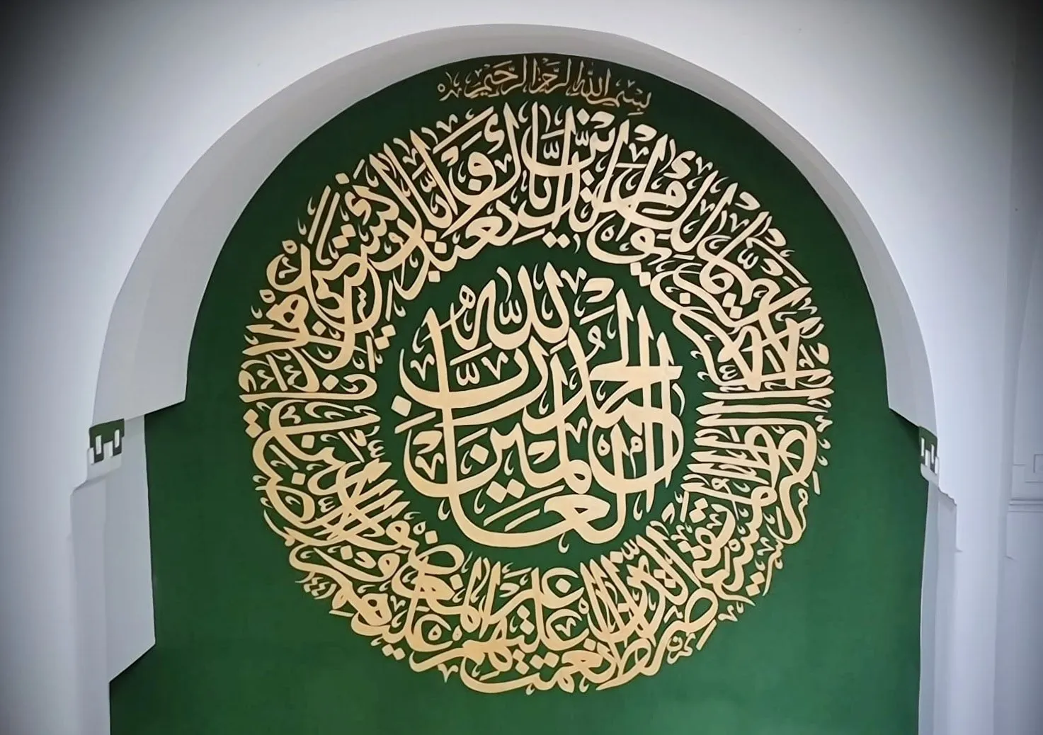 Surah Al-Fātiha in goud op diep groen.